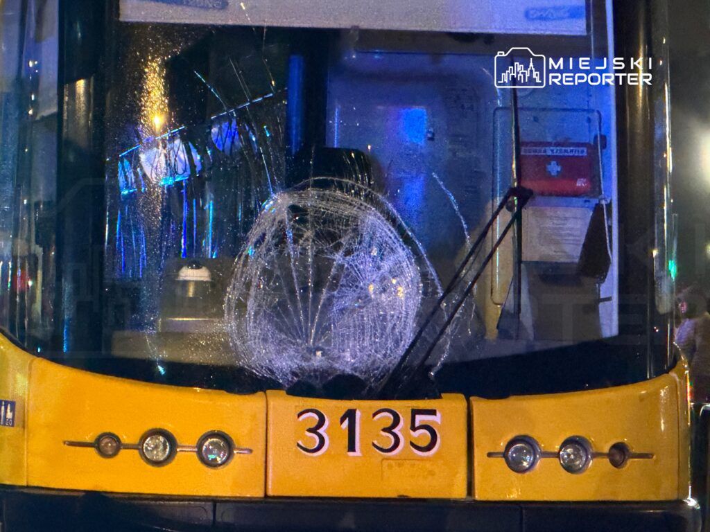 Zniszczona szyba przednia autobusu z numerem 3135, z widocznymi pęknięciami, w miejskim otoczeniu nocnym.