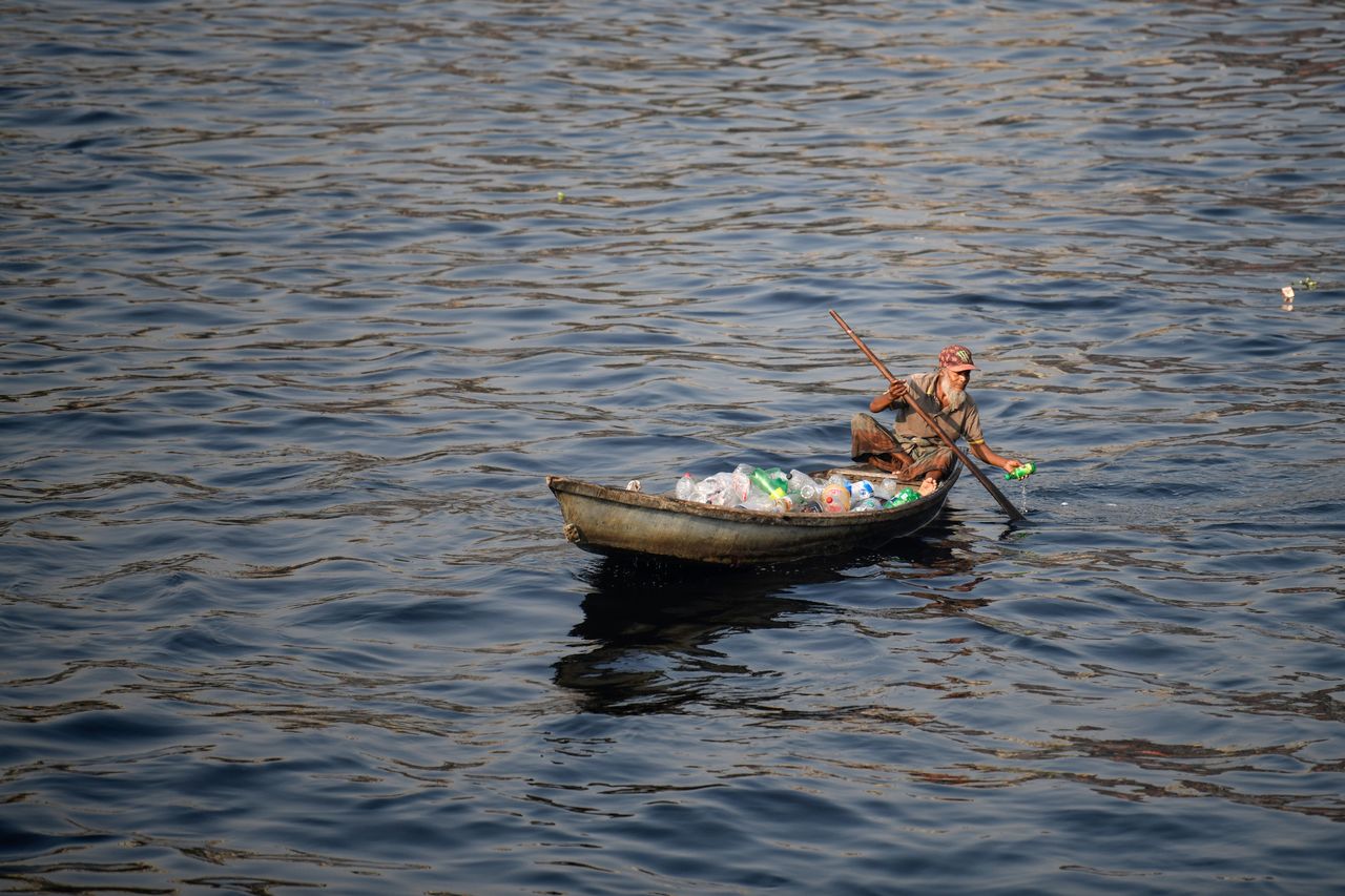 A man on a boat collects plastic bottles from the polluted river Buriganga in Dhaka.