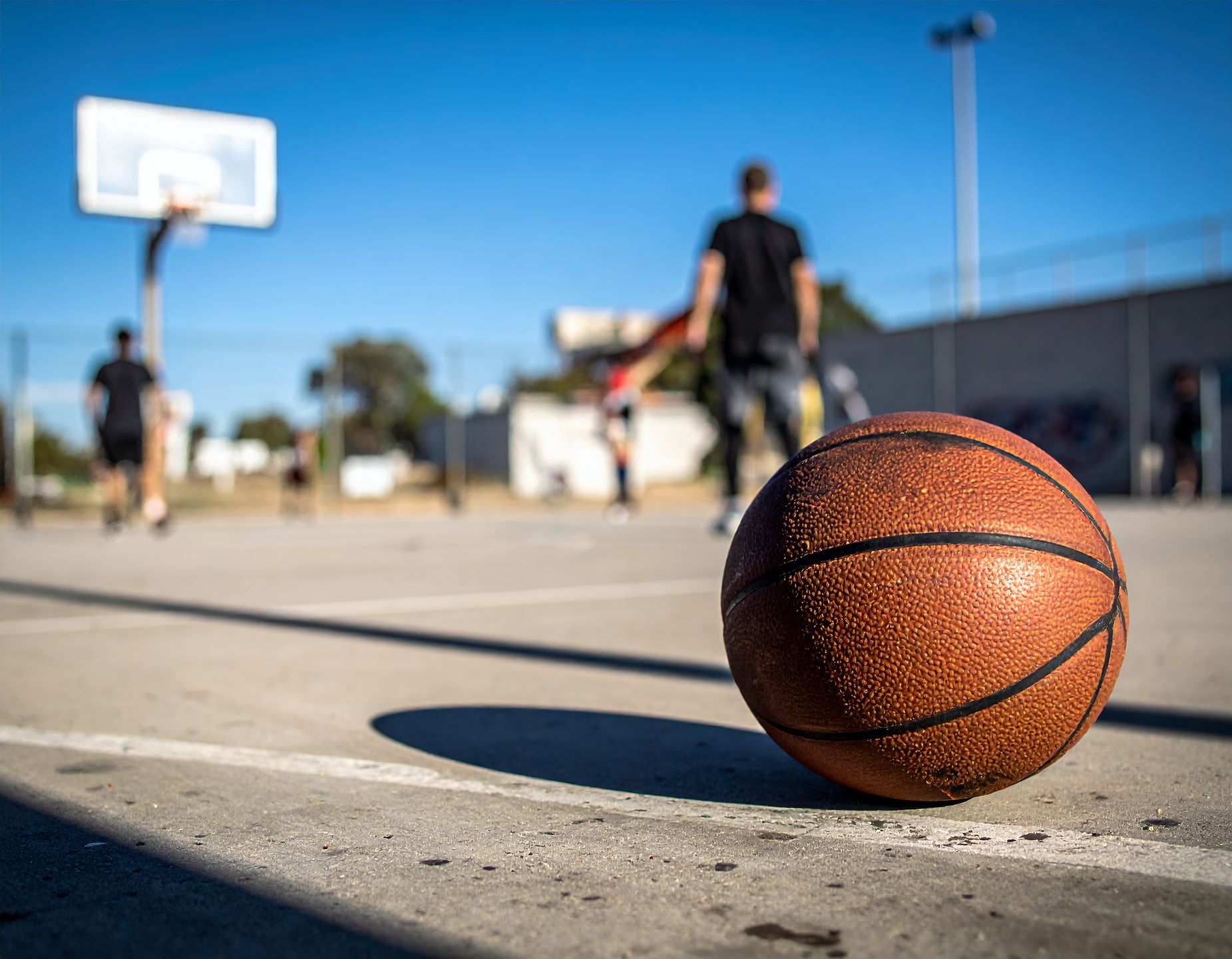 basketball, outdoor, court, streetball, recreation, sport, activity, ball, playing, game, exercise, fitness, competition, teamwork, summer, sunlight, urban, concrete, lines, hoop, net, leisure, fun, athlete, physical activity, training, practice, skills, playground, youth, weekend, day, bright, sunny, shadows, focus, close-up, perspective, action, dynamic, energy, lifestyle, healthy, community, neighborhood, public space