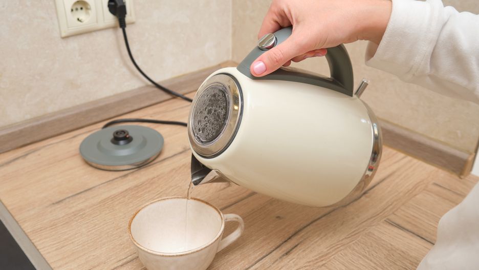Person pouring hot water from electric kettle into ceramic cup on a wooden kitchen countertop. Close-up shot of hand holding kettle. Home kitchen concept.Person pouring hot water from electric kettle into ceramic cup on a wooden kitchen countertop. Close-up shot of hand holding kettle. Home kitchen concept.ZHURAVLEV ANDREYkettle, electric, water, pour, hot, cup, ceramic, kitchen, hand, person, woman, countertop, wooden, home, appliance, steam, heat, close-up, indoors, drink, tea, coffee, boiling, morning, beverage, relaxation, time, handle, lid, plug, socket, power, breakfast, hydration, pouring, liquid, domestic, household, preparation, equipment, interior, lifestyle, table, cooking, utensil, heating, kitchenware, dish, kettle, electric, water, pour, hot, cup, ceramic, kitchen, hand, person, woman, countertop, wooden, home, appliance, steam, heat, close-up, indoors, drink, tea, coffee, boiling, morning, beverage, relaxation, time, handle, lid, plug, socket, power, breakfast, hydration, pouring, liquid, domestic, household, preparation, equipment, interior, lifestyle, table, cooking, utensil, heating, kitchenware, dish