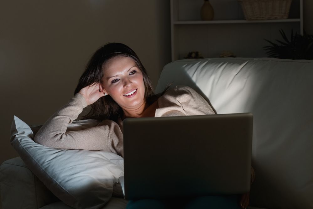 Zdjęcie kobiety oglądającej telewizję na laptopie pochodzi z serwisu Shutterstock