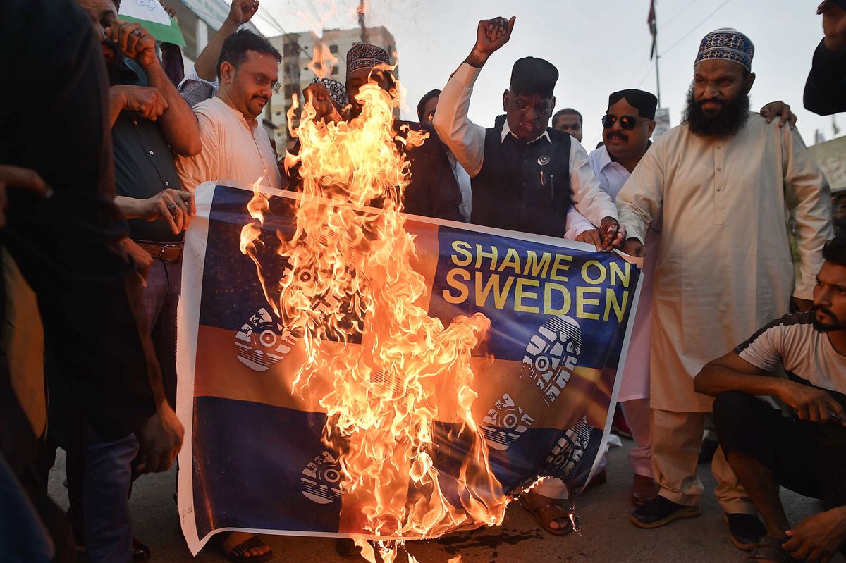 Demonstranci palą makietę szwedzkiej flagi podczas protestu przeciwko spaleniu kopii Koranu w Szwecji 