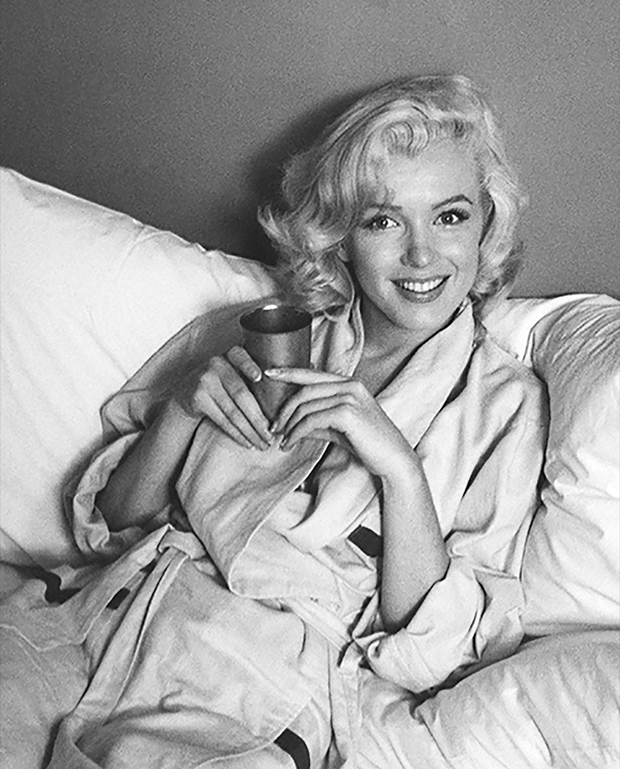 Marilyn Monroe sfotografowana w łóżku z kubkiem napoju