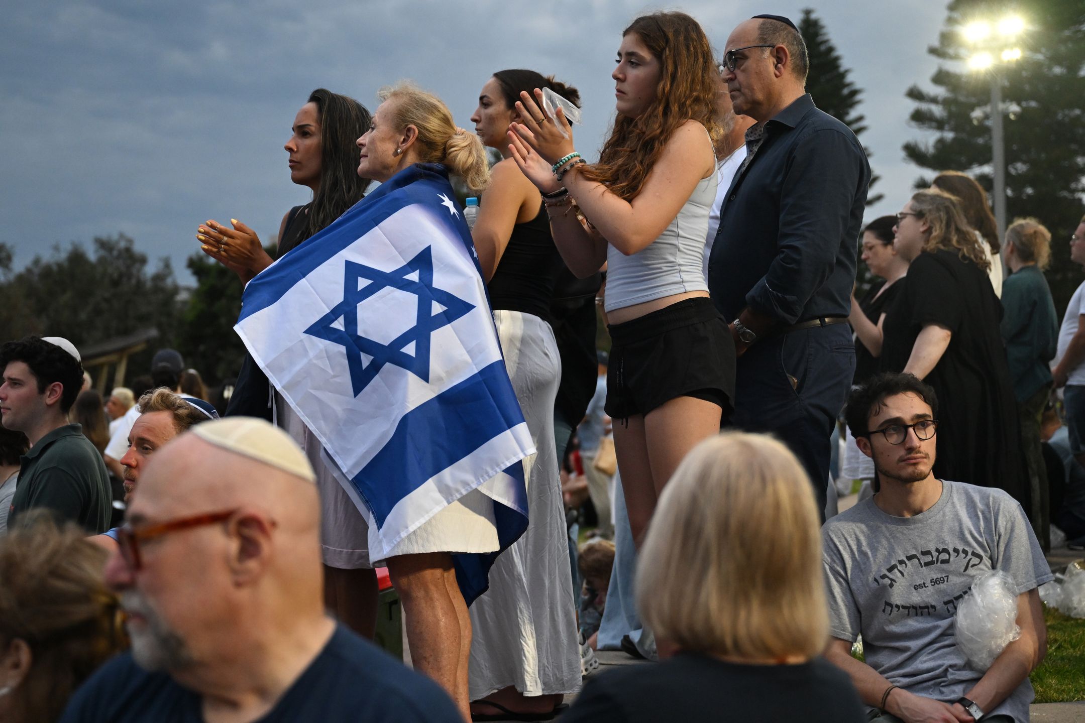 Vigil honors Bondi Beach victims in Sydney
epa12606865 People attend the National Day of Reflection vigil and commemoration for the victims and survivors of the Bondi Massacre at Bondi Beach in Sydney, Australia, 21 December 2025.  EPA/DEAN LEWINS AUSTRALIA AND NEW ZEALAND OUT 
Dostawca: PAP/EPA.
DEAN LEWINS
BONDI PAVILION, FLORAL MEMORIAL, FLOWERS, FLOWER MEMORIAL, NSW, GUNMEN, GUNMAN, SHOOTER, SHOOTERS, ATTACK, SHOOTING INCIDENT, TRAGEDY, VICTIMS, FATALITIES, MASSACRE, JEWISH COMMUNITY, HATE CRIME, ANTISEMITISM, MASS SHOOTING, BONDI BEACH SHOOTING, RELIGIOUS ATTACK, VIOLENCE, MOURNING, COMMUNITY TARGETED, DEATHS, FLORAL TRIBUTE, CASUALTIES, MASS KILLER, TERRORIST, TERRORISM, BONDI VIGIL AND COMMEMORATION, NATIONAL DAY OF REFLECTION