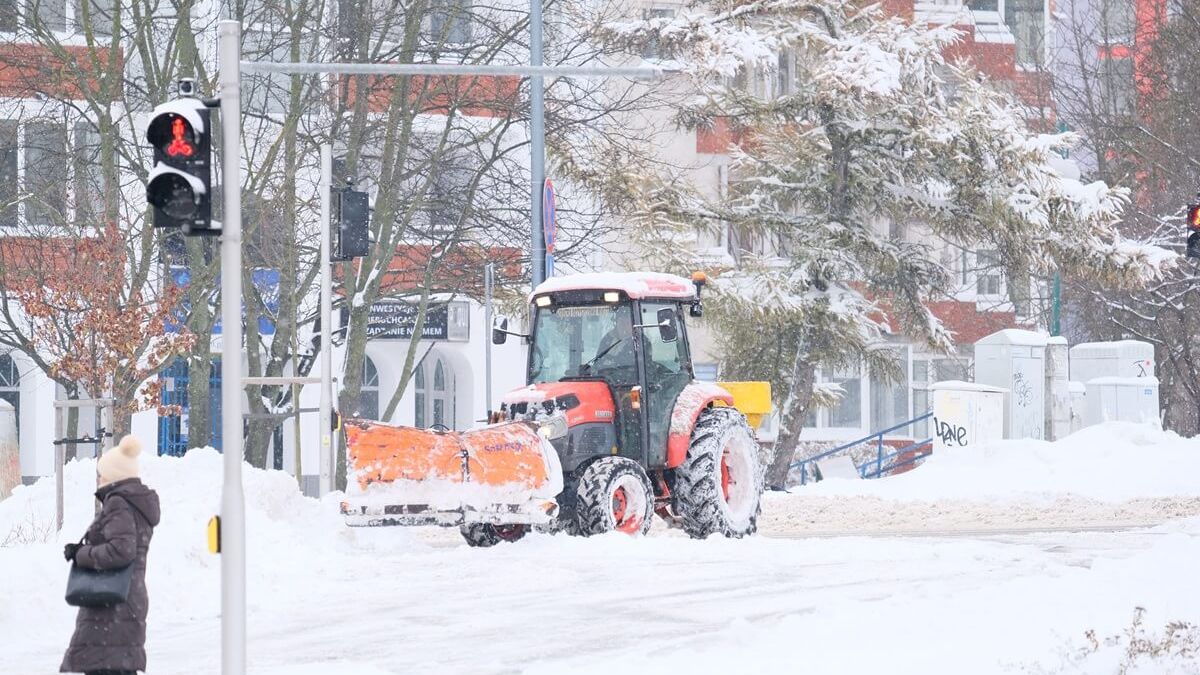 Opłużony traktor odśnieża chodniki i przejście dla pieszych