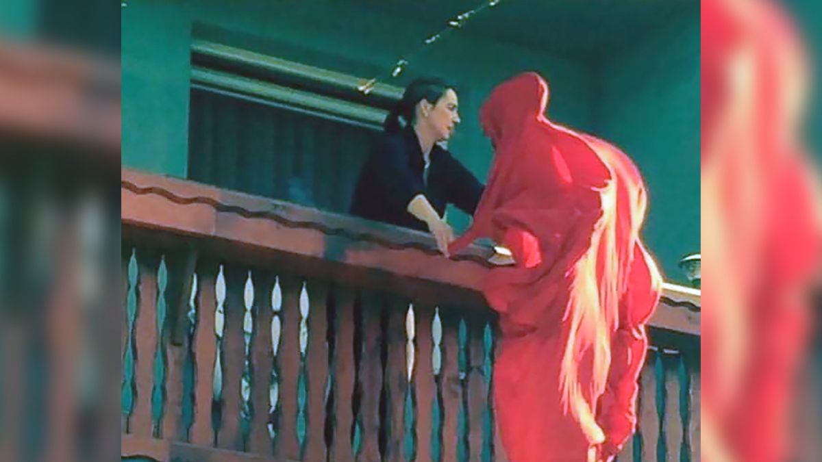 Kobieta trzepiąca prześcieradło.