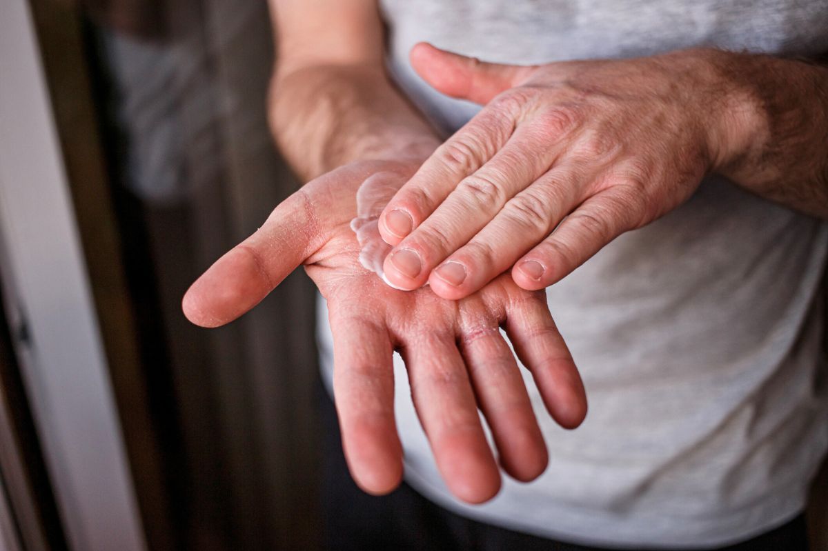 The man rubs his hands with cream.