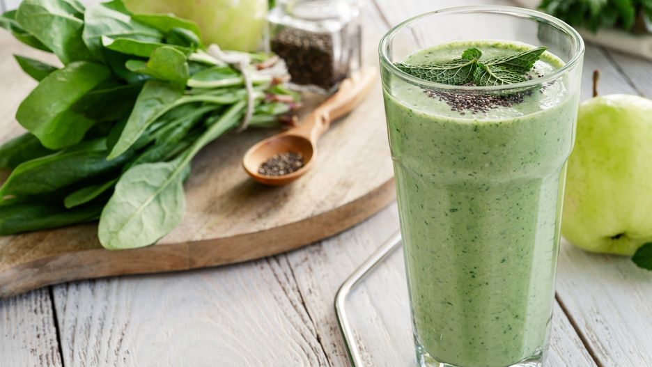 Green smoothie with fresh leaf vegetables, fruits, herbs, and chia seeds