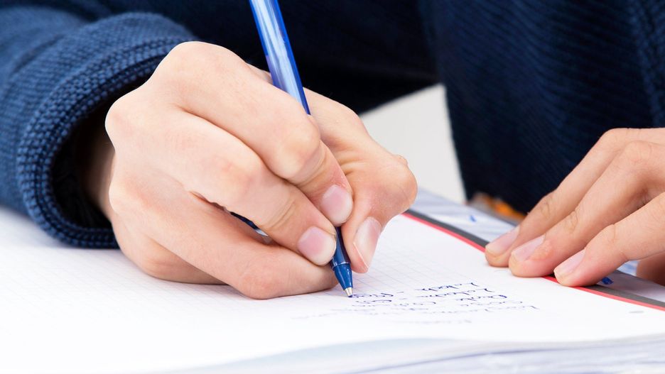 closeup of the hand of the child writing with the pen