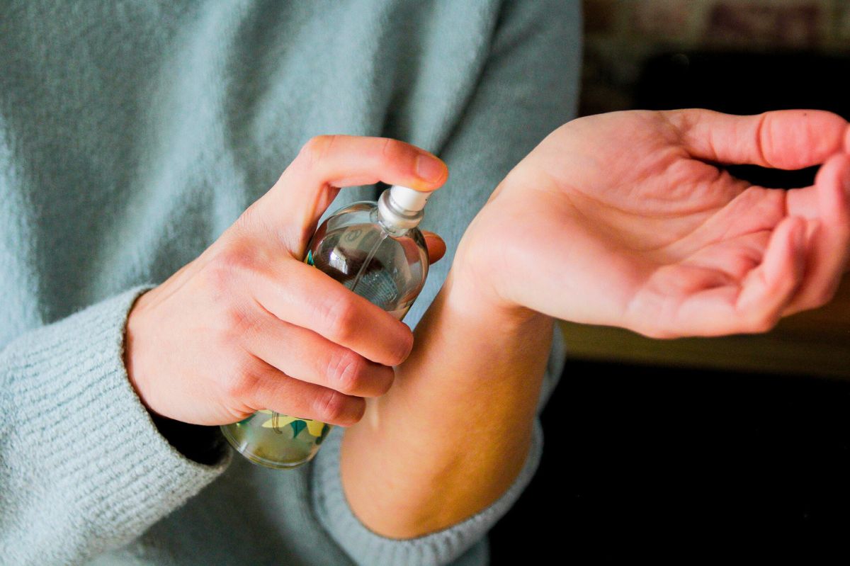 The woman sprays perfume on her hand.