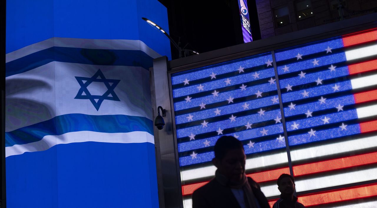 People walk past a billboard showing an Israeli flag displayed in connection to a rally in support of Israel in Times Square, New York