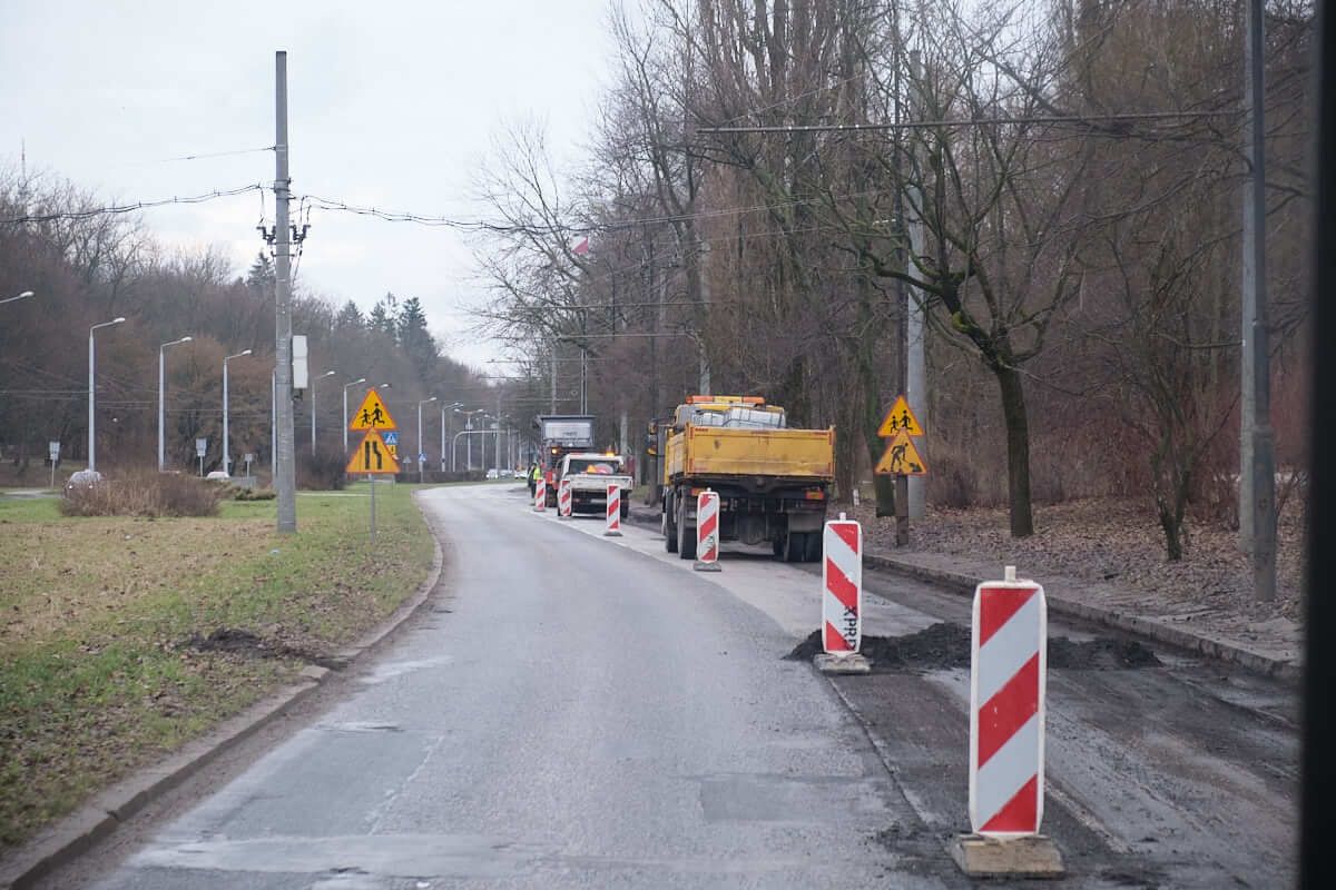 sfrezowany odcinek ulicy głębokiej. w oddali samochód ciężarowy i frezarka drogowa