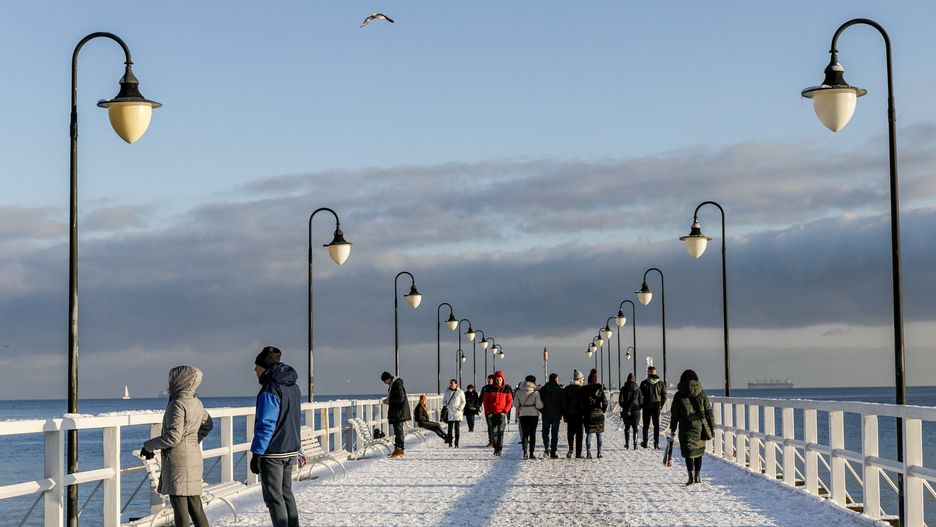 GDYNIA, POLAND - 2022/12/10: People walk along the Gdynia Orlowo pier covered with snow. (Photo by Volha Shukaila/SOPA Images/LightRocket via Getty Images)