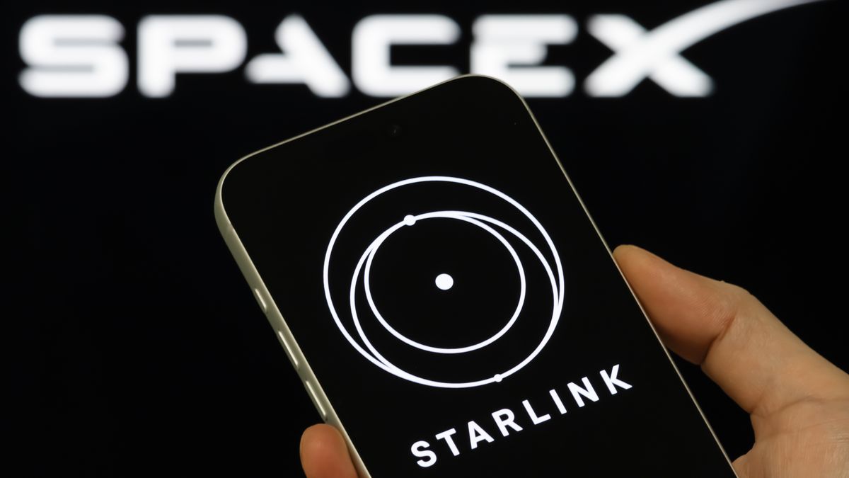 CHONGQING, CHINA - FEBRUARY 3: In this photo illustration, a person holds a smartphone displaying the Starlink logo, with the SpaceX brand visible in the background, on February 3, 2026, in Chongqing, China. The image follows reports that Elon Musk's aerospace company SpaceX is combining with his artificial intelligence venture xAI, a deal that would place xAI's assets, including the social media platform X, under SpaceX as Musk moves to consolidate his technology businesses and expand SpaceX's presence across communications, data and digital platforms. (Photo illustration by Cheng Xin/Getty Images)