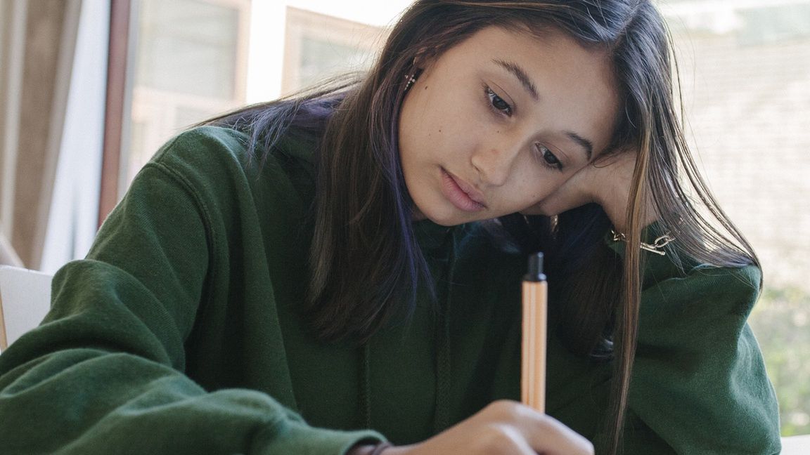 High School Student Concentrating On Work In ClassA high school student concentrating on her work during class and resting her head on her hand.Willie B. Thomas