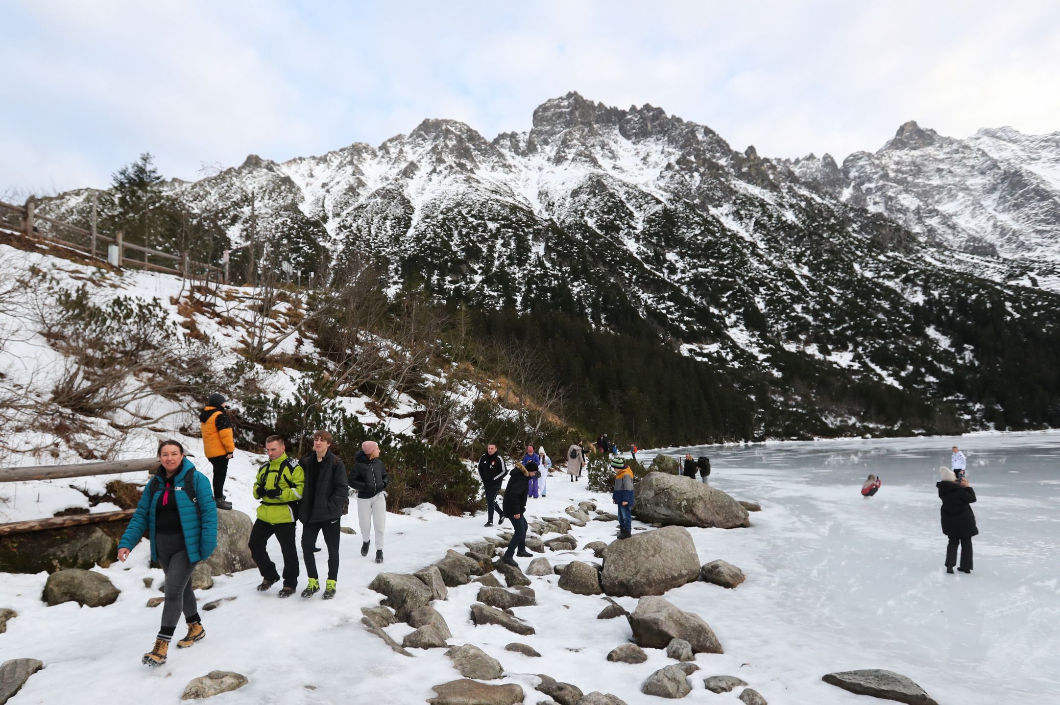 Tatry, Morskie Oko, 26.12.2022. Turyści na tafli lodu na jeziorze Morskie Oko w Tatrach, 26 bm. Tatrzański Park Narodowy ostrzega przed wchodzeniem na zamarznięte górskie jeziora � z powodu panujących w ciągu dnia dodatnich temperatur lód jest bardzo cienki i grozi załamaniem. (jm) PAP/Grzegorz Momot