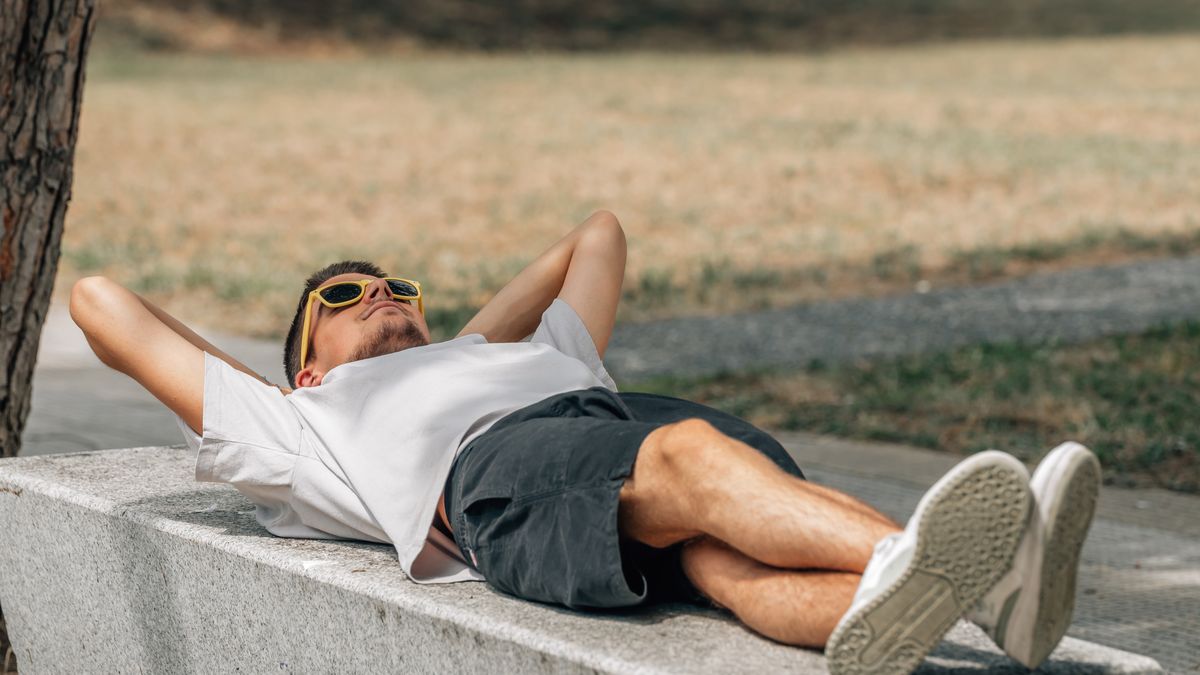 Na zdjęciu mężczyzna leżący na murze w okularach przeciwsłonecznych