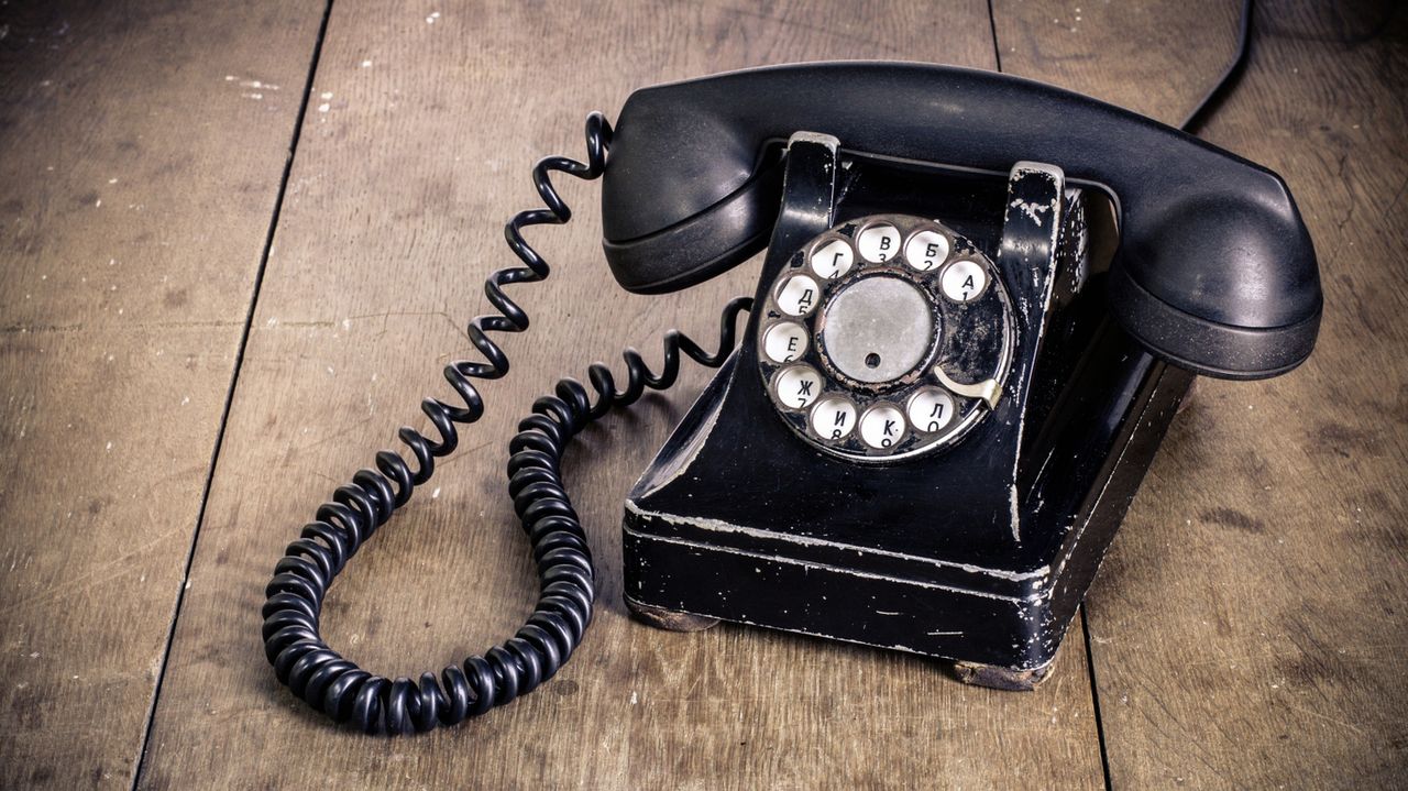 Vintage black phone on old wooden table background