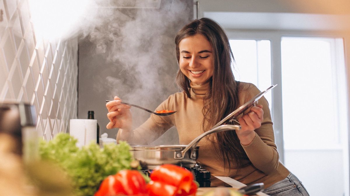 Uśmiechnięta kobieta gotuje zupę