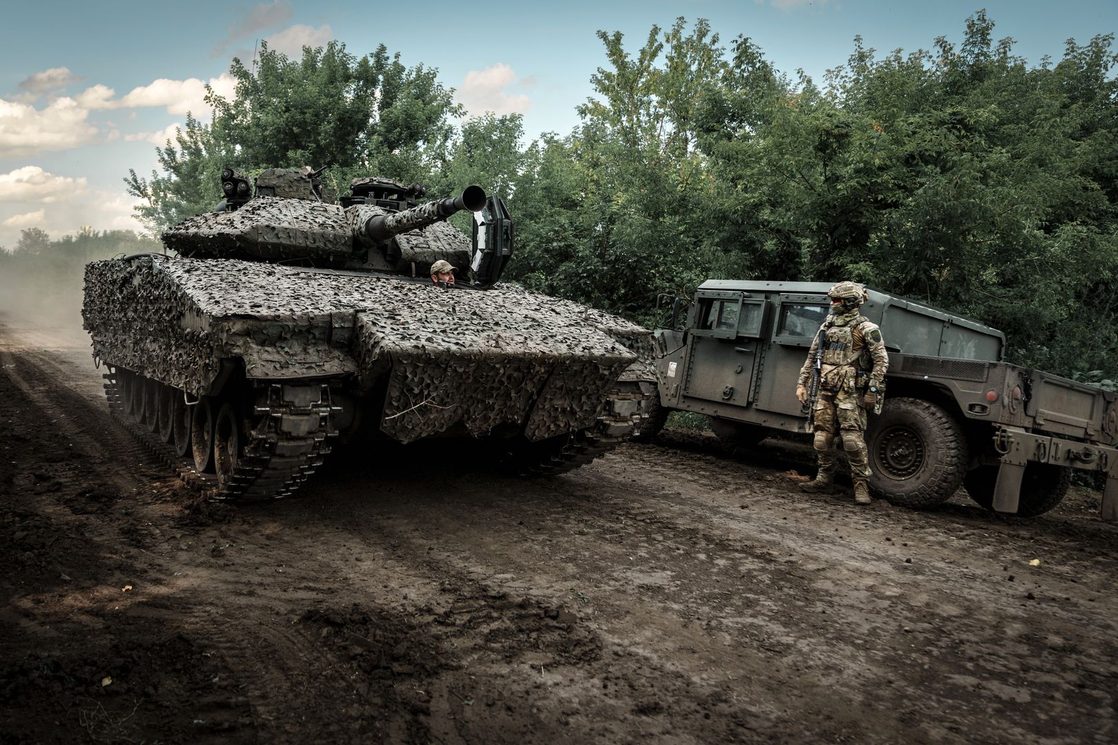 NEVSKE, UKRAINE - JULY 2: Swedish CV90 infantry fighting vehicle drives a dirt road past a Ukrainian military member standing with weapon next to a combat vehicle on July 2, 2023 in Nevske, Luhansk Oblast, Ukraine. Ukraine received armored vehicles as part of international military assistance programs to help defend itself against the ongoing Russian invasion. (Photo by Serhii Mykhalchuk/Global Images Ukraine via Getty Images)