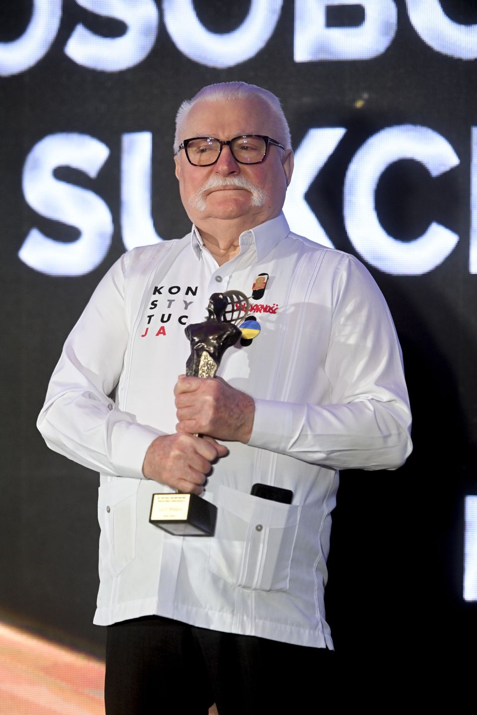 Gala, koszula z naszywkami, nagroda, okulary w czarnych oprawkach, statuetka