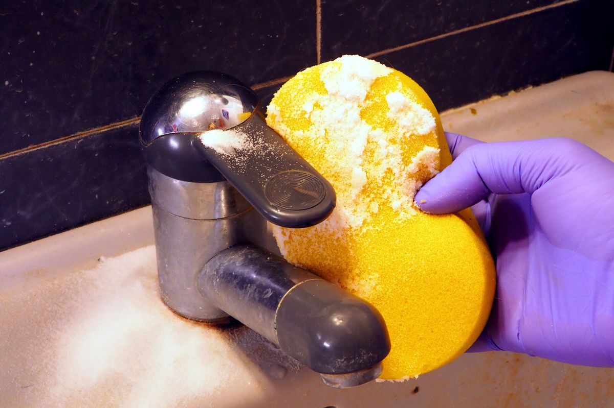 The woman is washing the tap in the bathroom.