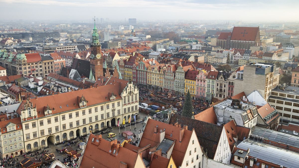 Aerial view of market square at Christmas and historic city center in Wroclaw, Poland
Aerial view taken above the historic city center of Wroclaw, Poland, looking over the Market Square (Rynek) and the surrounding old town at Christmas time. Dense red rooftops, historic townhouses, churches, and towers spread across the urban landscape, with streets radiating from the main square. Overcast daylight reveals architectural details and the layered structure of the city, representing historic European urban heritage and a prominent cityscape.
Nico De Pasquale Photography