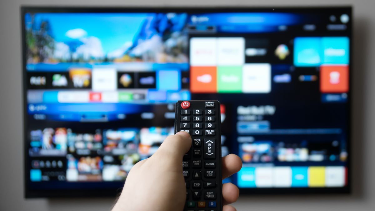 Na zdjęciu telewizor i osoba z pilotem przed nim