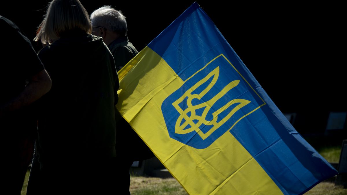 People are seen with a Ukrainain flag at the Soviet Military Cemetery in Warsaw, Poland on 09 May, 2024. Protesters interrupted Russian ambassador Sergey Andreyev's visit to the monument with loud screams while wearing dresses with the names of bombed Ukrainian cities and covered in stage blood. (Photo by Jaap Arriens/NurPhoto via Getty Images)