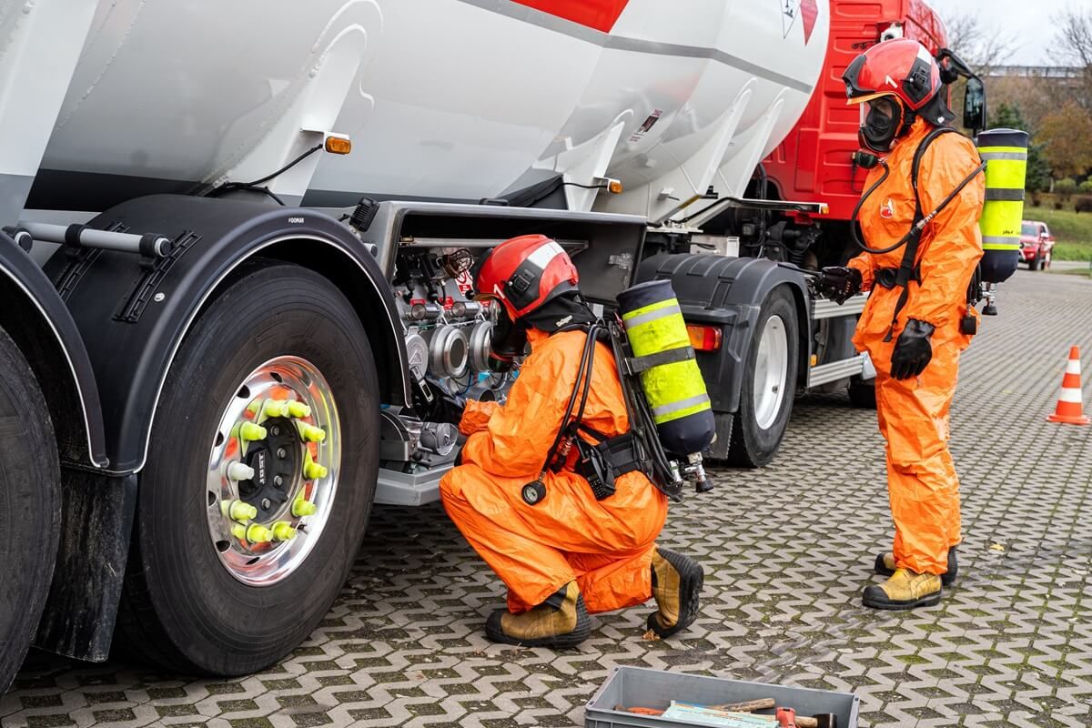 Strażacy w kombinezonach przy cysternie na paliwo Orlen