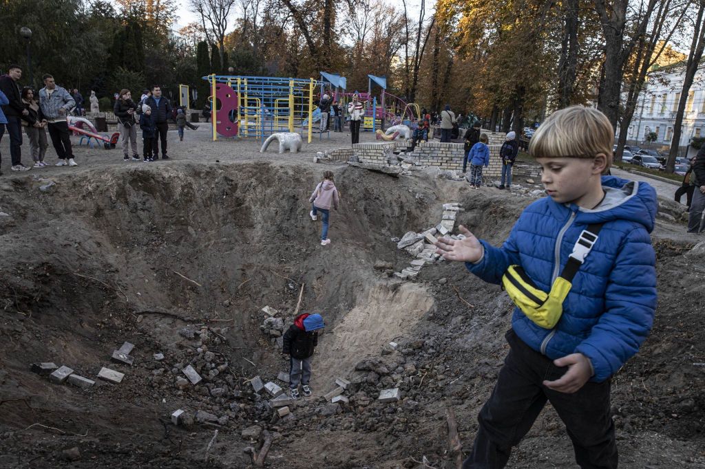Dzieci bawią się w leju po ruskiej bombie w parku Szewczenki w Kijowie