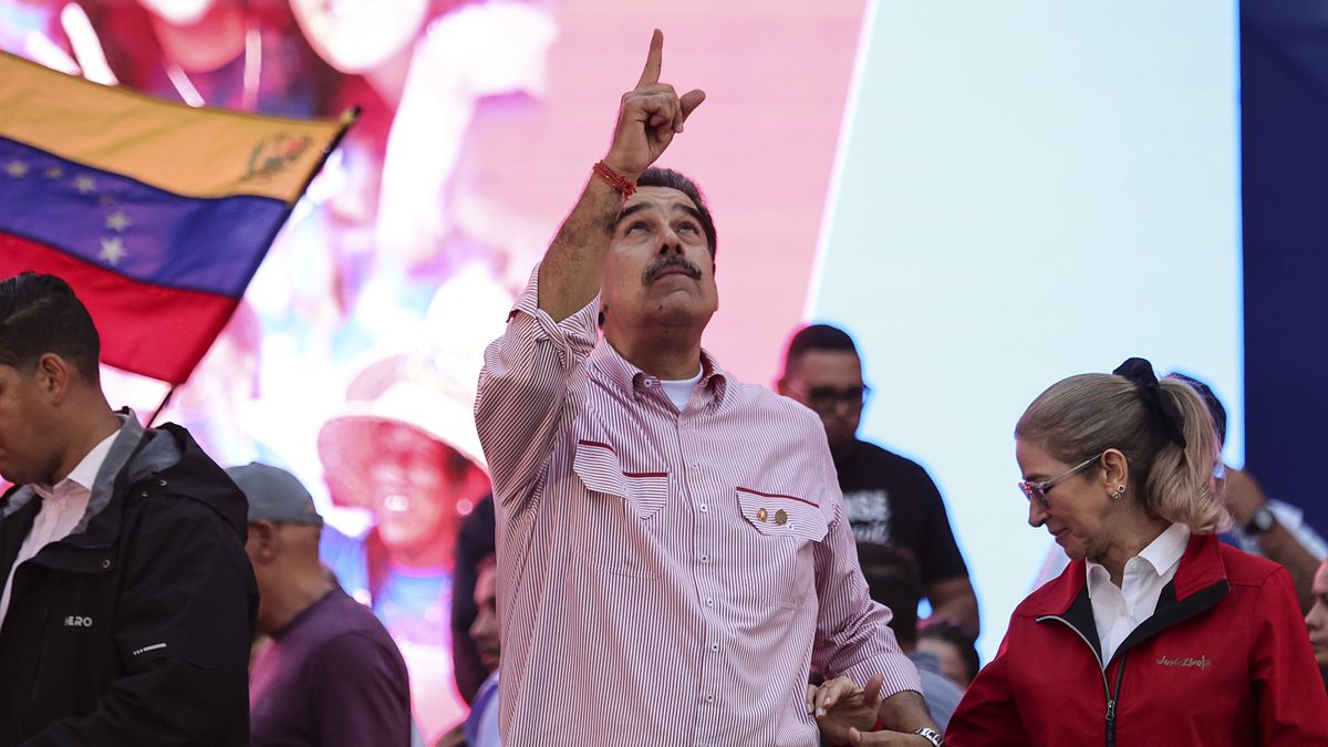 CARACAS, VENEZUELA - DECEMBER 1: President Nicolas Maduro of Venezuela makes a gesture skywards alongside his wife and First Lady Cilia Flores during a protest to show him support on December 1, 2025 in Caracas, Venezuela. Supporters gathered at Miraflores to show support and to be part of the swearing-in of the 'Integral Bolivarian Community Commands.' (Photo by Jesus Vargas/Getty Images)