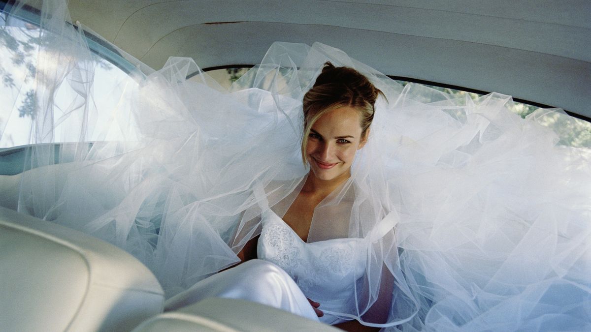 Panna młoda uśmiecha się, jadąc w limuzynie