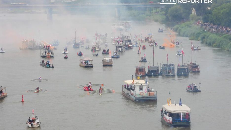 Wielka flota łodzi i statków płynąca po rzece, w tle dym i flagi, na wodzie widoczne wiosła.