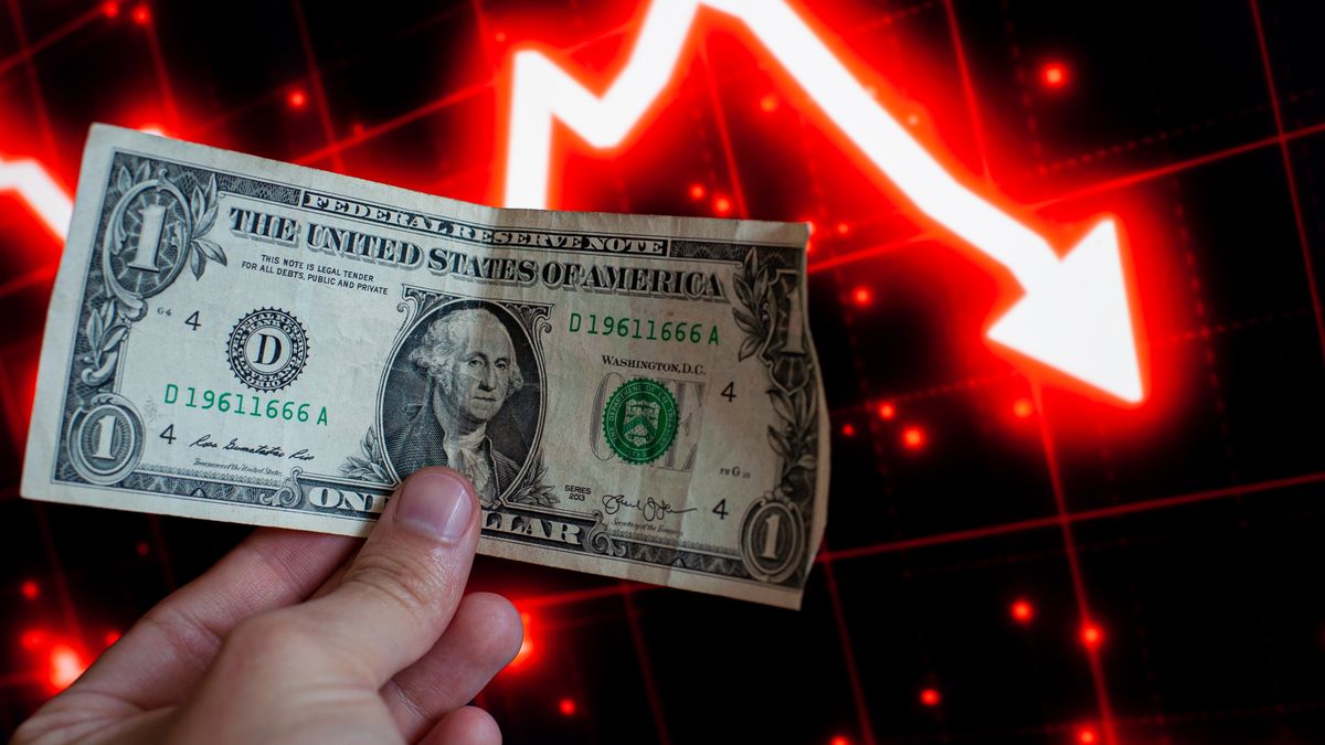 A United States Dollar note seen with a red stock market graph. (Photo by Sebastian Barros/NurPhoto via Getty Images)
