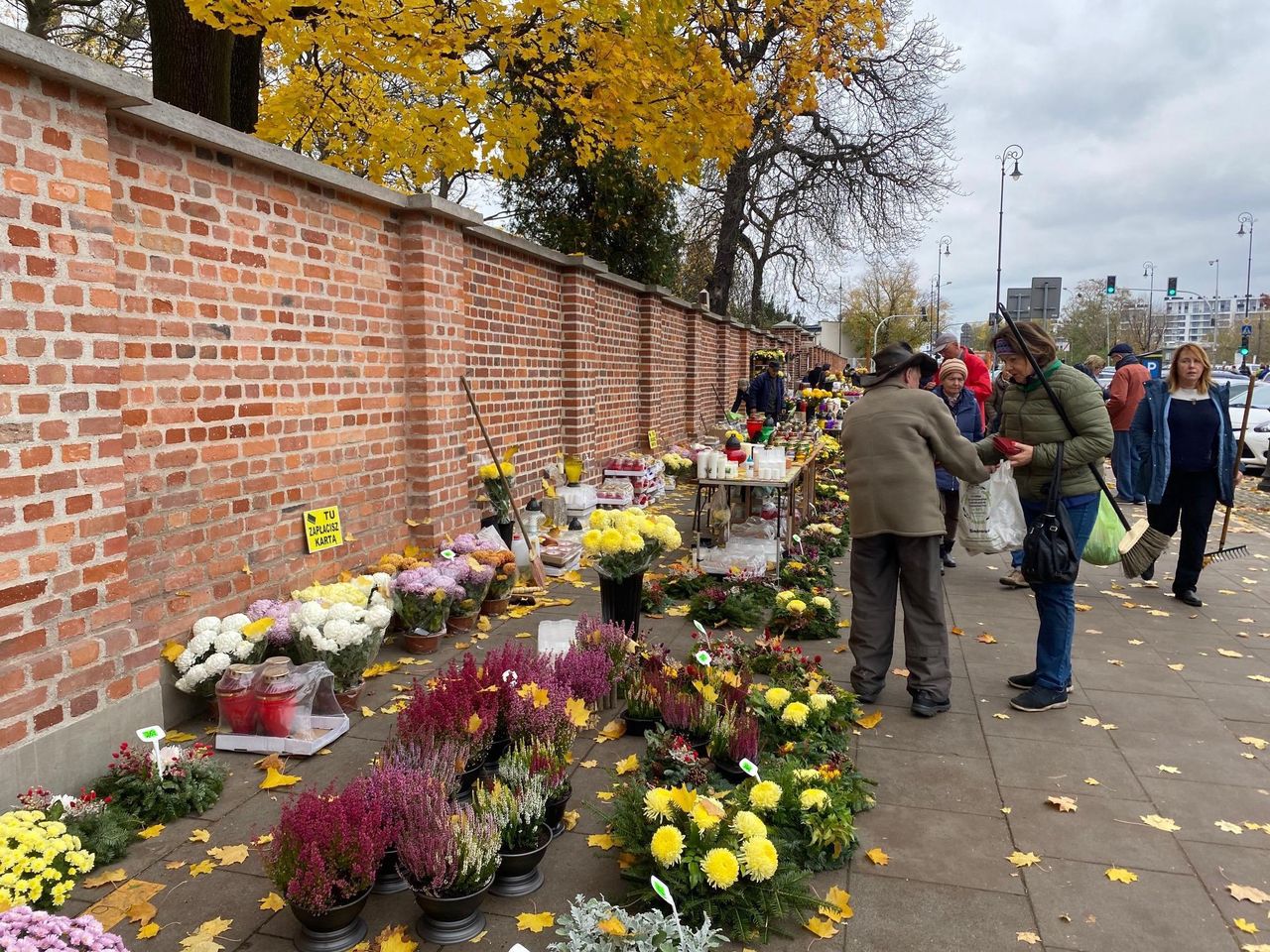 Przed murem Starych Powązek ostatnie dni października to czas ogromnego ruchu. Ludzie ruszają porządkować groby i udekorować, jak należy (Barbara Kwiatkowska)