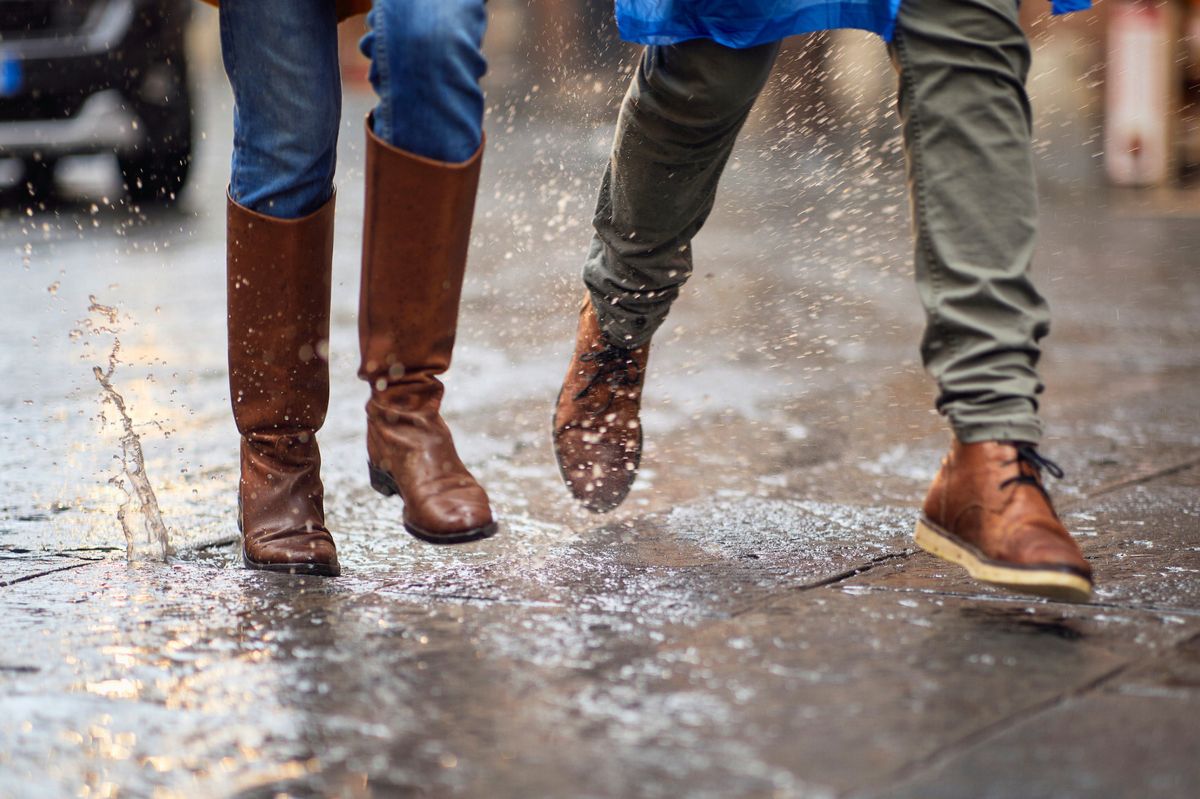 A man and a woman are walking down the wet street.