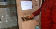 Automat wymienia monety na banknoty. Ludzie ustawiają się w kolejkach