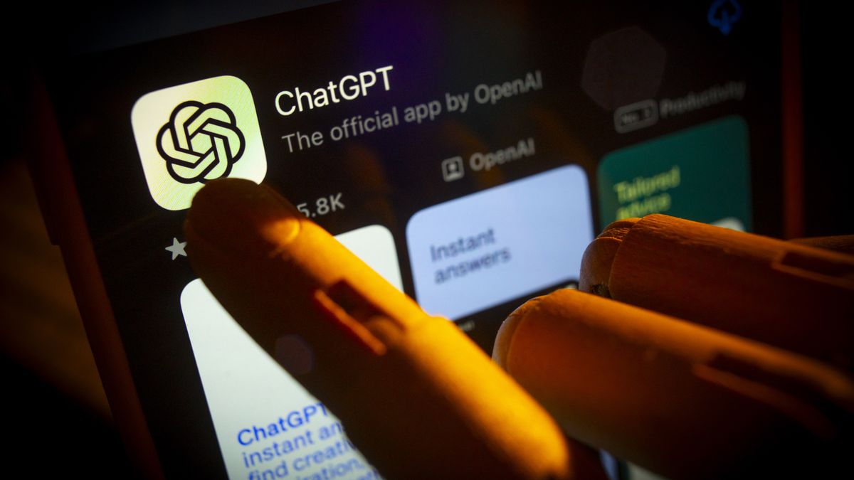 An artificial hand is seen pointing a finger onto a mobile phone screen displaying the Apple App Store with the Chat GPT app in this photo illustration on 29 October, 2023 in Warsaw, Poland. (Photo by Jaap Arriens/NurPhoto via Getty Images)
