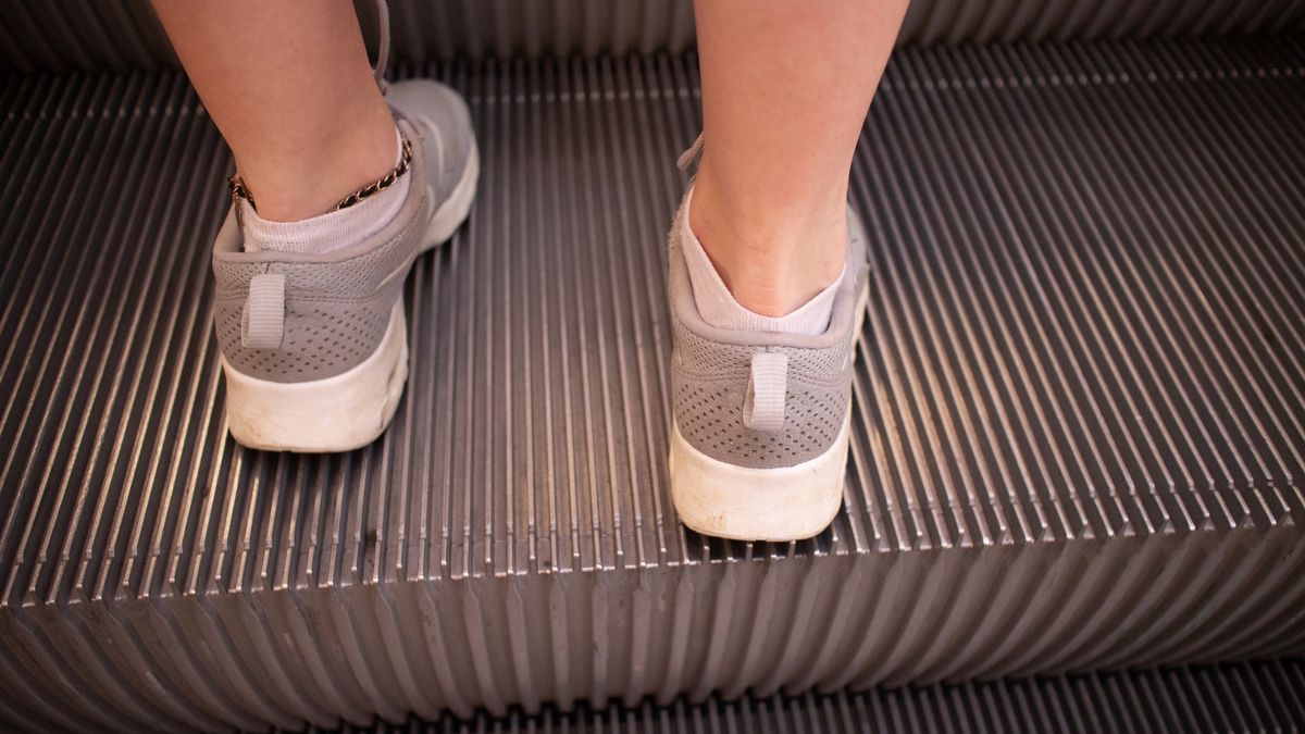 Young woman in training or running shoes standing on the steps of an escalatorYoung woman in training or running shoes standing on the steps of an escalatorRaylipscombeactivity