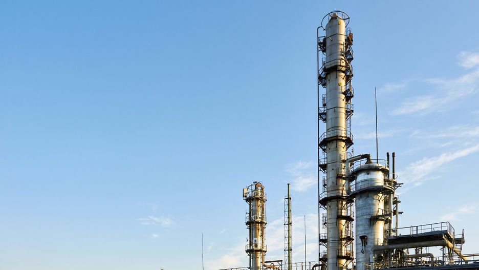 Oil refinery chemical plant wide view with copyspace over blue evening sky with clouds background. Methanol production distillation refinery columns industrial background with copyspace.