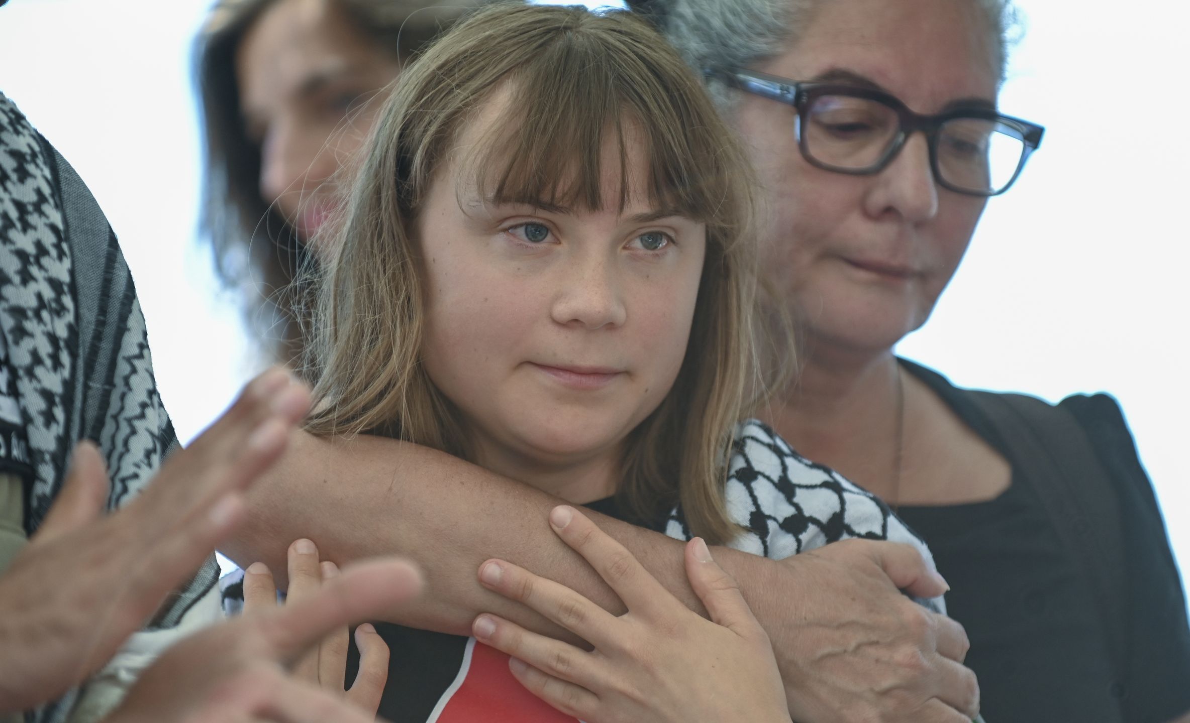 CATANIA, ITALY - JUNE 01: Greta Thunberg, embraced by a woman, joins the ceremony shortly before departing for Gaza, wearing a traditional keffiyeh on June 01, 2025 in Catania, Italy. Swedish activist Greta Thunberg is among those who will attempt to sail to Gaza on a boat organized by the Freedom Flotilla Coalition (FFC), in a bid to break Israel's blockade of the Palestinian territory. Freedom Flotilla had to abort a previous journey in early May after it said its boat came under attack by drones in international waters near Malta. (Photo by Fabrizio Villa/Getty Images)