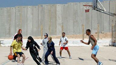 Palestyńczycy grają w koszykówkę pod murem bezpieczeństwa