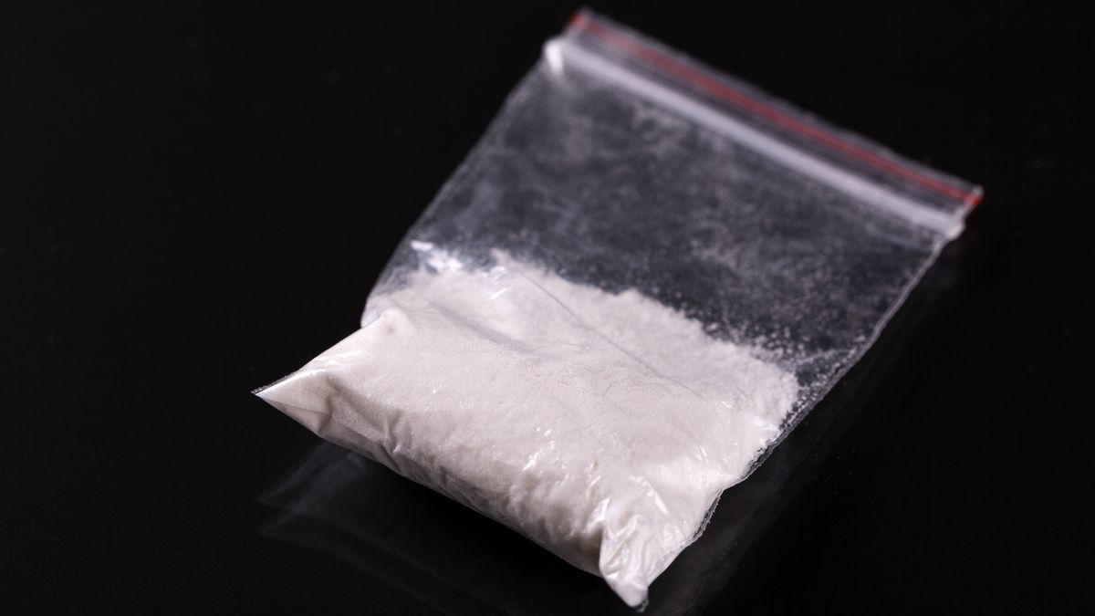Cocaine in plastic packet on black background, closeup