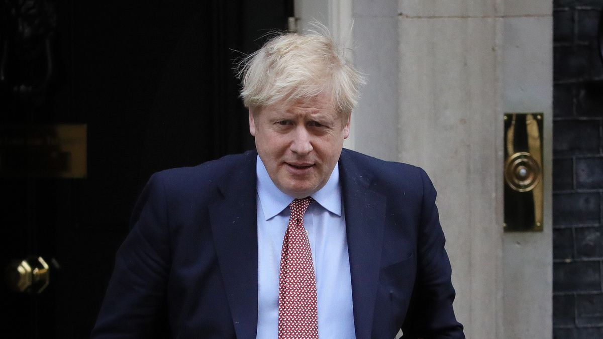 Premier Wielkiej Brytanii Boris Johnson rozmawia z personelem medycznym i siada na łóżku.
