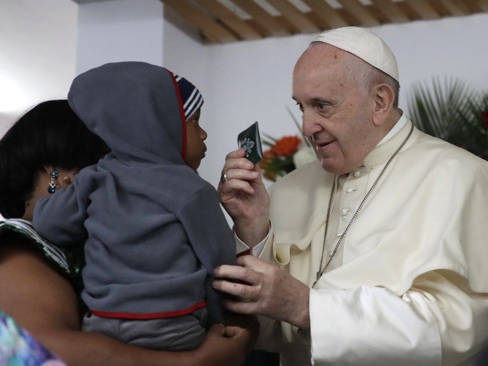 Papież Franciszek wręcza dziecku pamiątkę podczas spotkania z kobietami i dziećmi z wirusem HIV. 