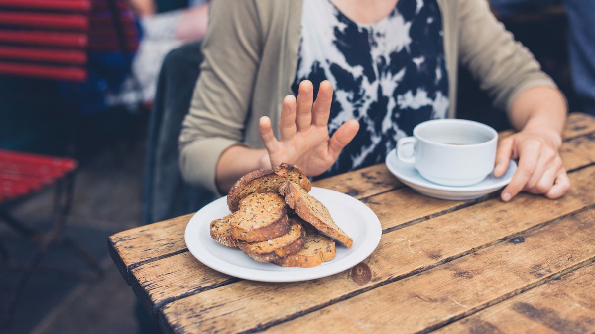 Young woman on gluten free diet is saying no thanks to toast in a cafe