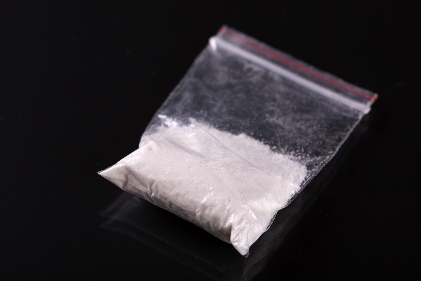 Cocaine in plastic packet on black background, closeup