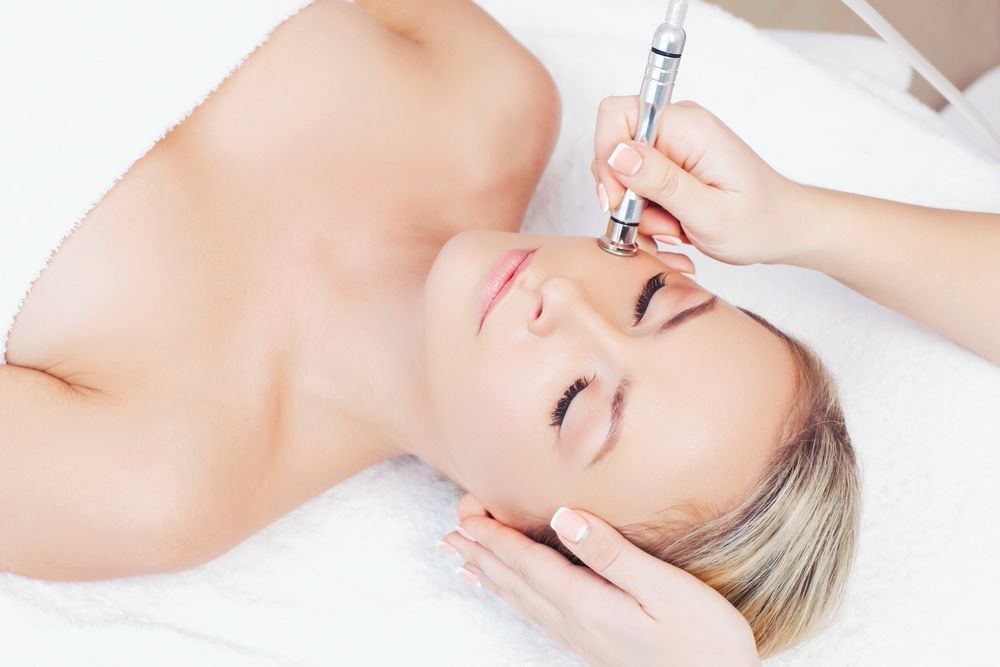 Hardware cosmetology. Closeup portrait of female face with closed eyes getting microdermabrasion procedure in a beauty parlour. 