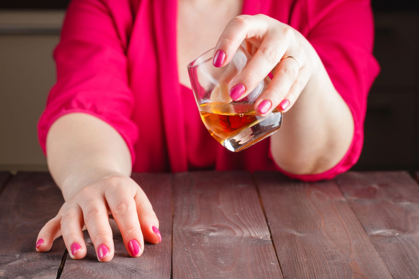Woman drink whiskey from glass on wooden table